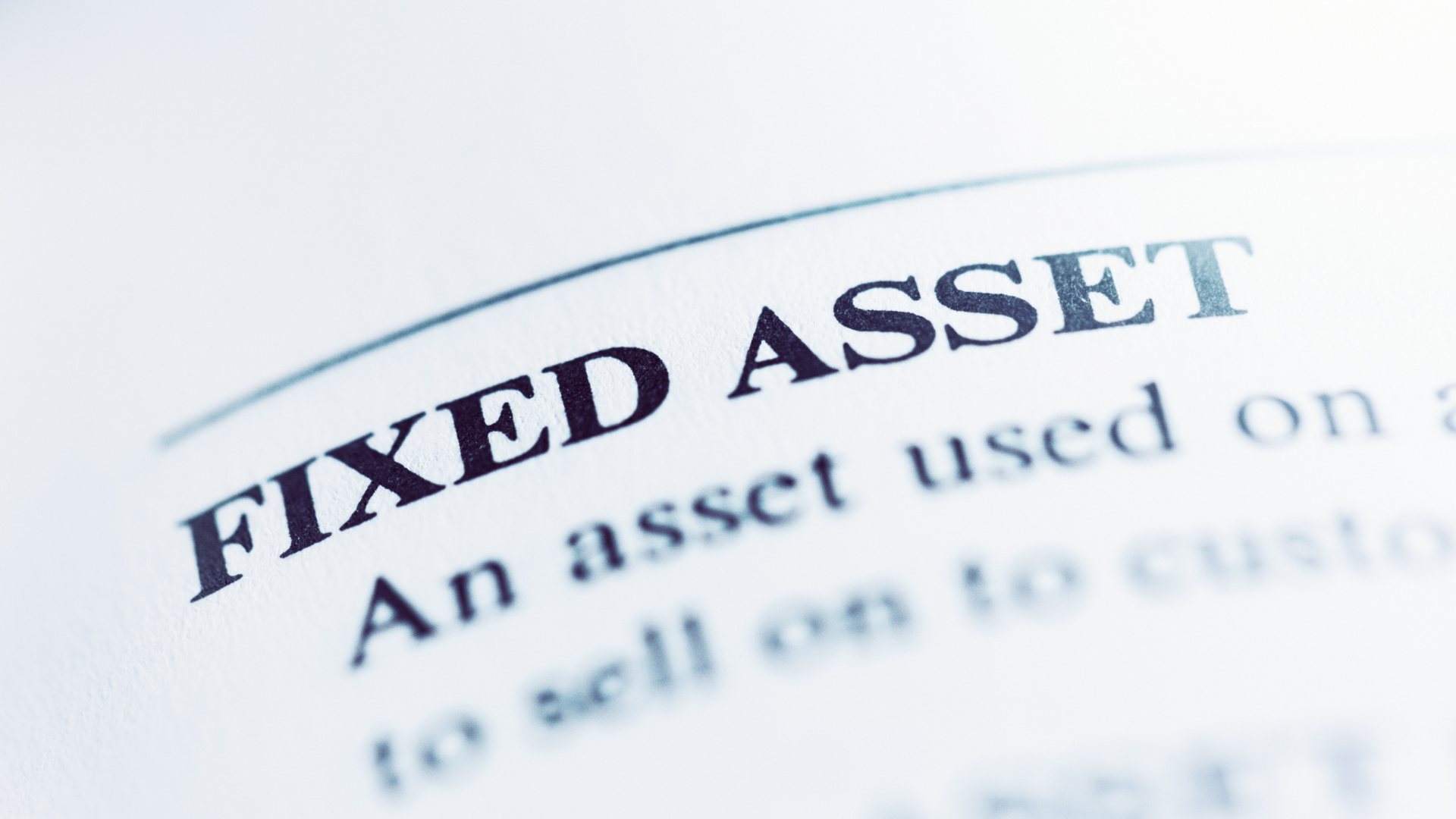 Close-up of a printed page with the heading "FIXED ASSET" in bold, highlighting how business basics and key business principles are explained for entrepreneurs, with partially visible descriptive text below.