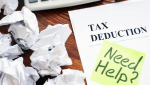 A document labeled "Tax Deduction" with a sticky note reading "Need Help?" sits on a desk near crumpled papers and a calculator, hinting at the stress of CRA audit preparation.